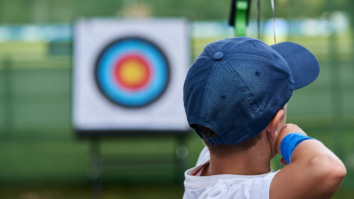 Archer aiming at a target — adjacent spine grades decide whether arrows group at distance